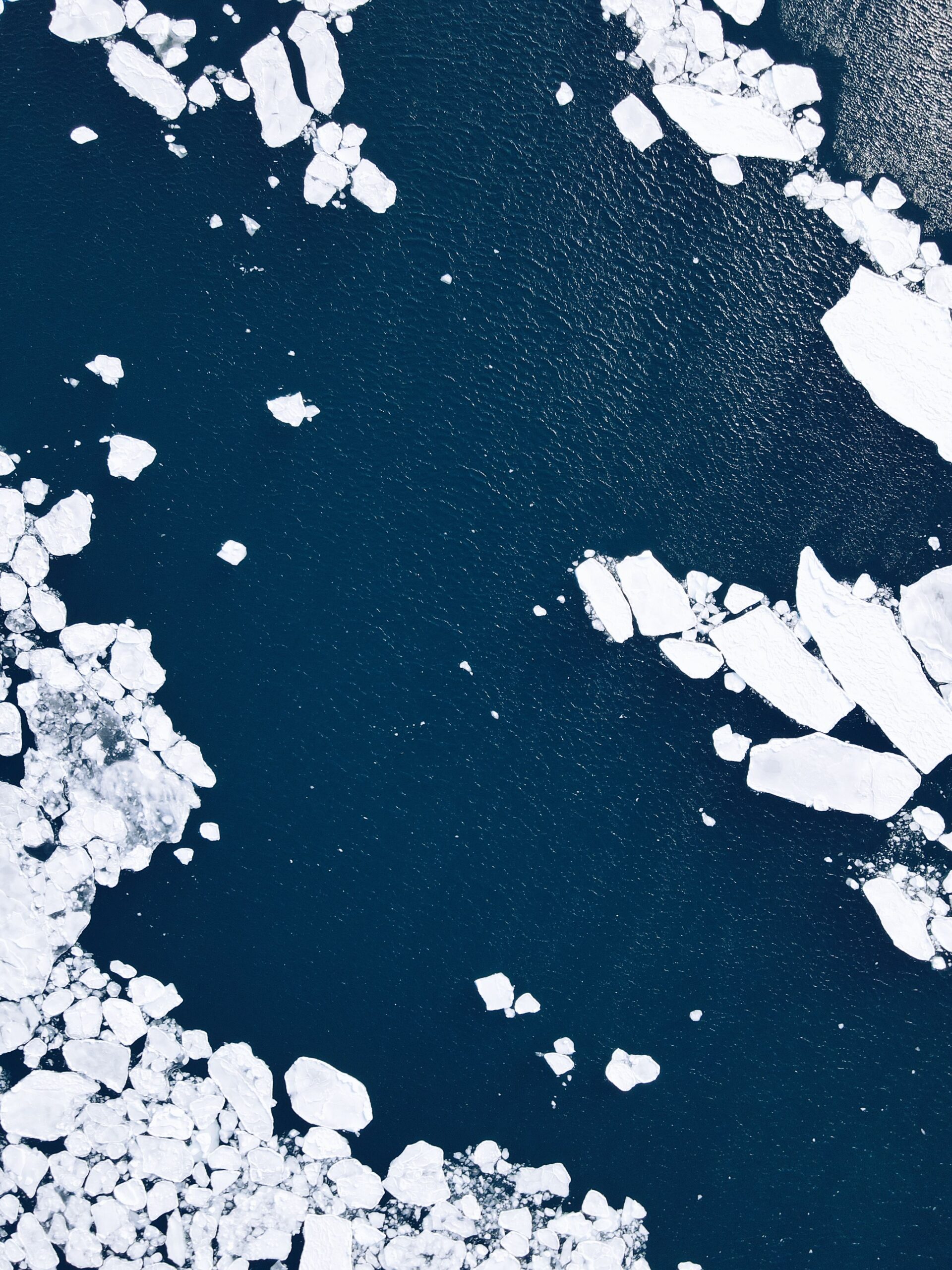 Aerial view of white ice floes separated by channels of dark blue water