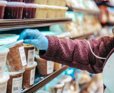 Shopper reading the label on a packaged frozen food in a grocery store