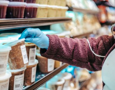 Shopper reading the label on a packaged frozen food in a grocery store