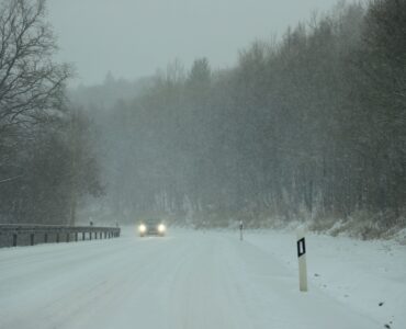 Car headlights shining through heavy snow on a winter road
