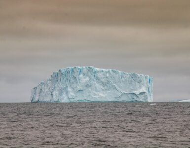 Large iceberg rising from dark Antarctic waters beneath a cloudy sky