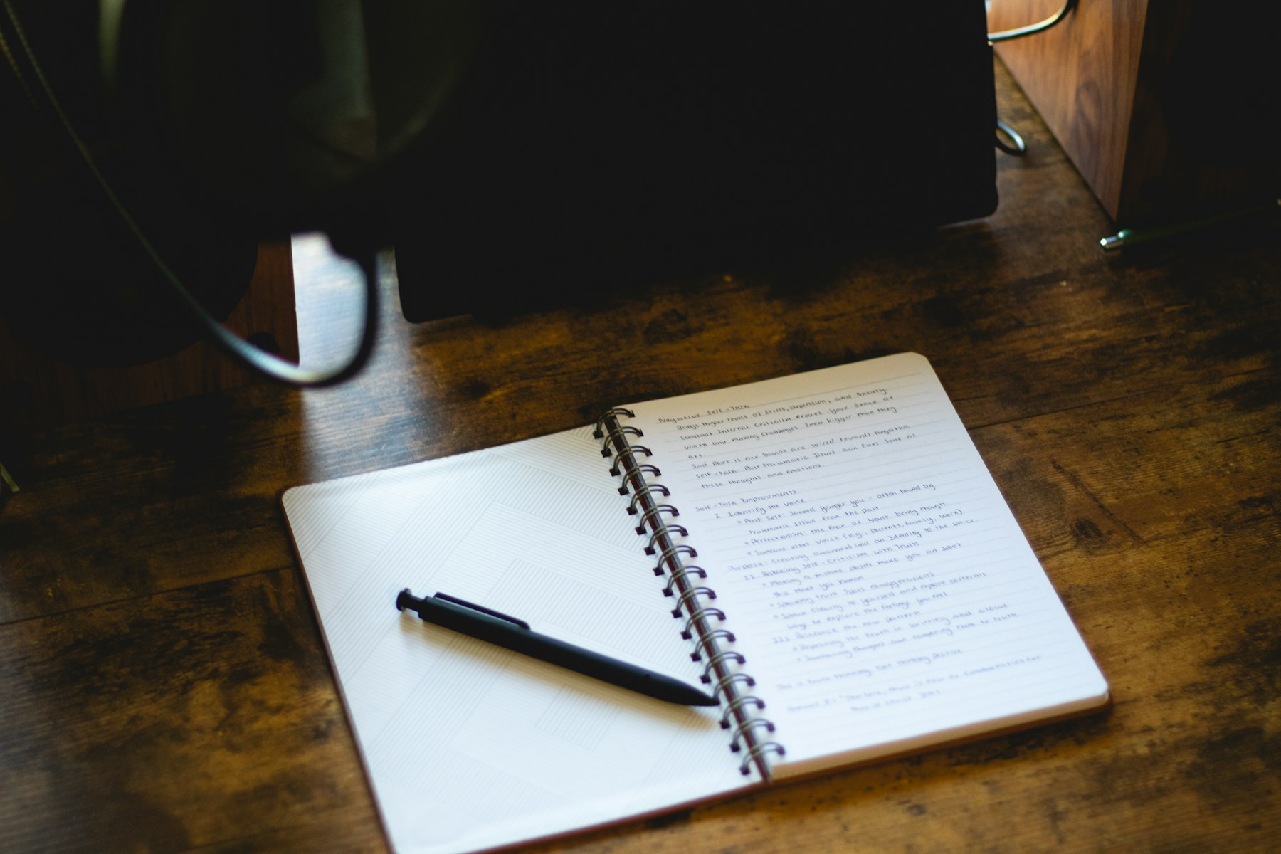 An open lined notebook and pen on a wooden desk