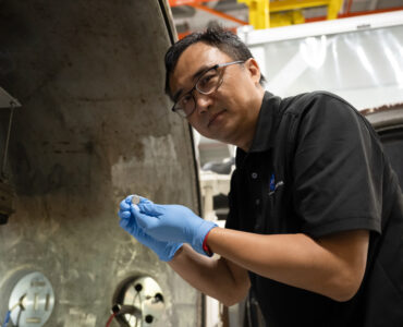 NASA researcher Yi Lin holds a small SPEARS solid-state battery after thermal-vacuum testing.