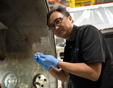 NASA researcher Yi Lin holds a small SPEARS solid-state battery after thermal-vacuum testing.