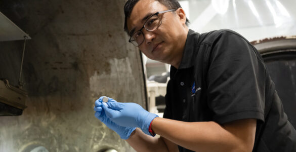 NASA researcher Yi Lin holds a small SPEARS solid-state battery after thermal-vacuum testing.