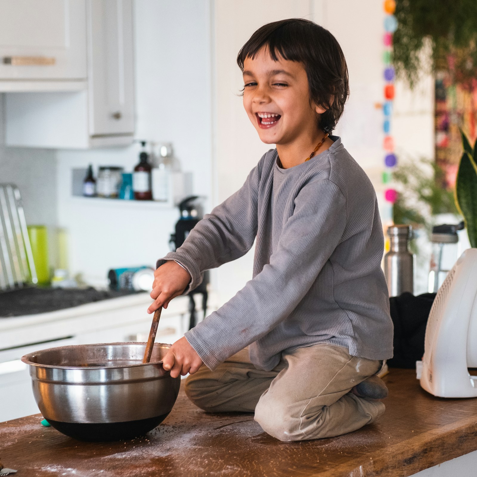 A young cook stirring ingredients in a bowl on a kitchen counter
