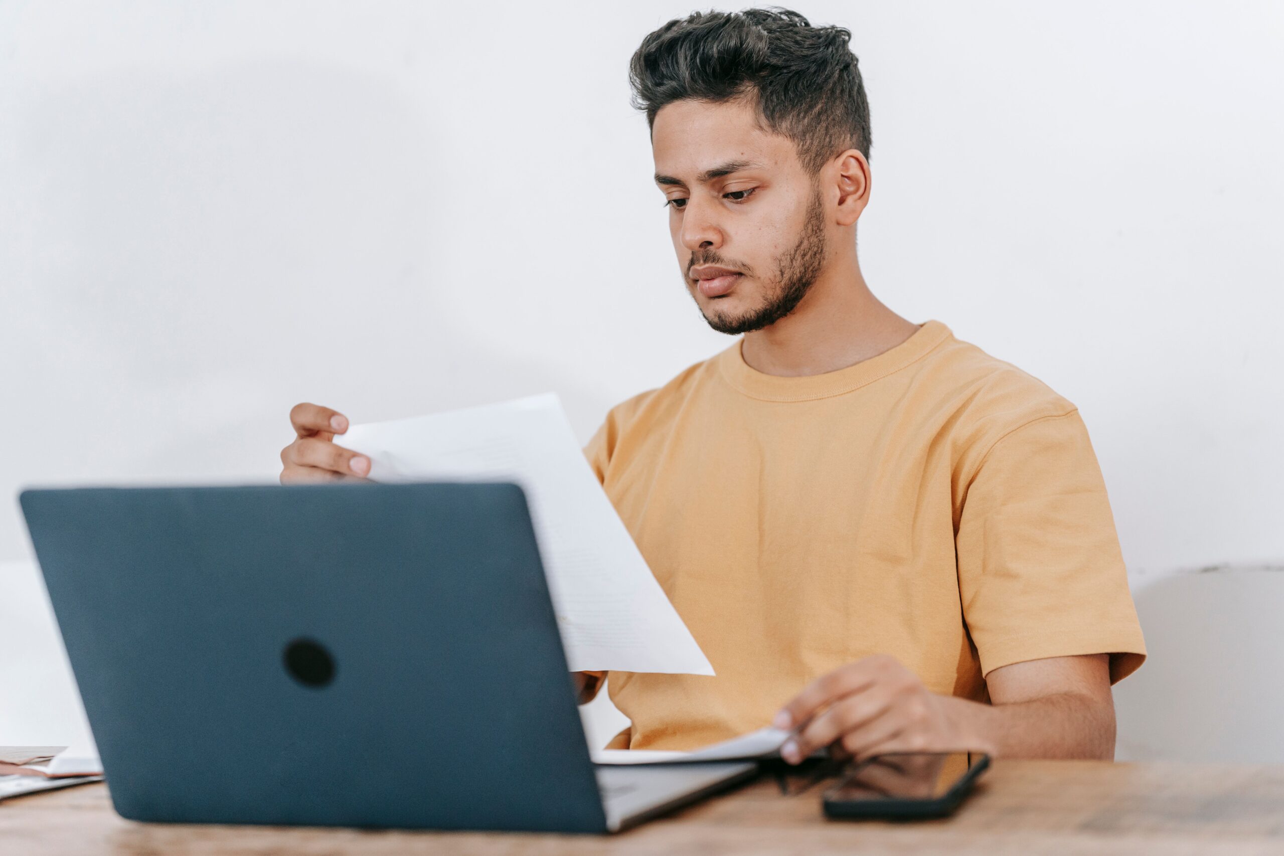 Student comparing a printed document with information on a laptop