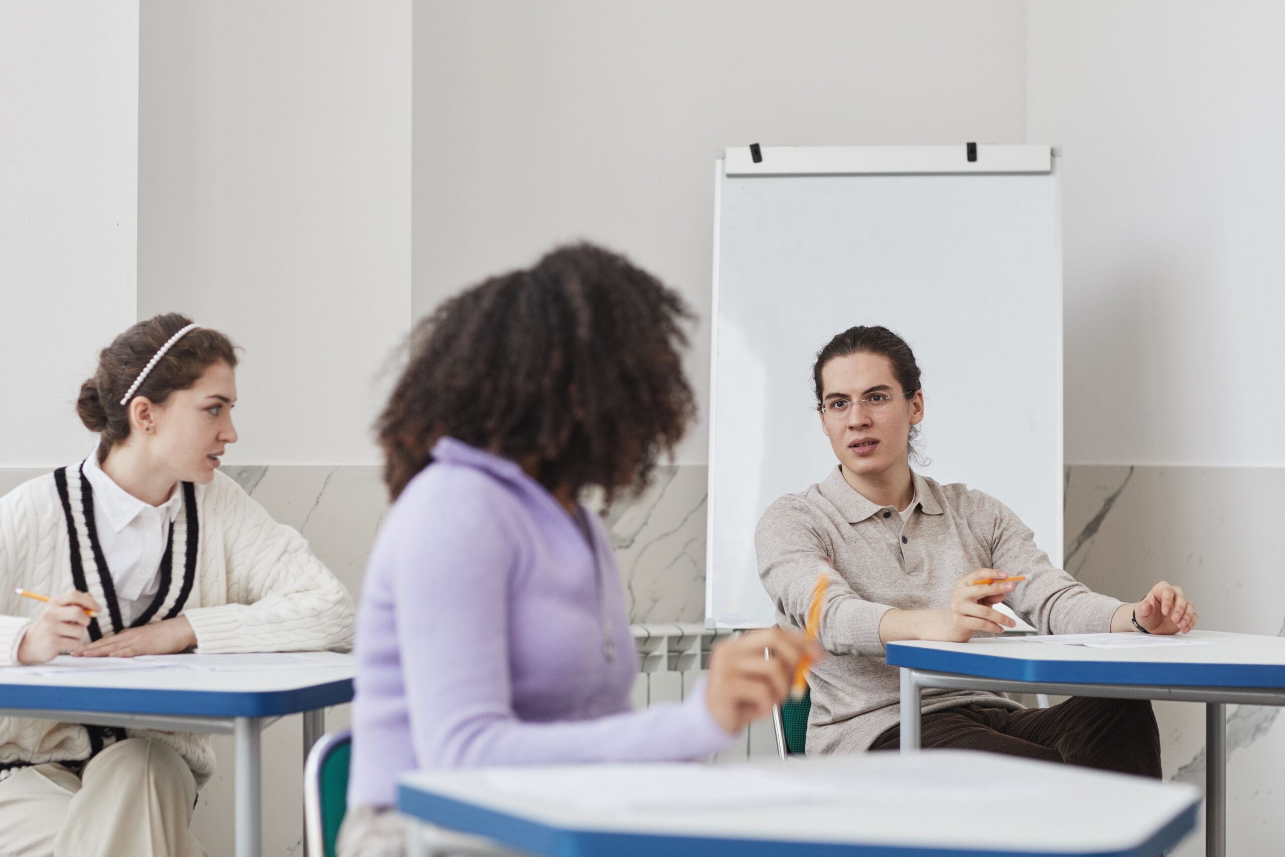 Three university students having a group conversation in a classroom