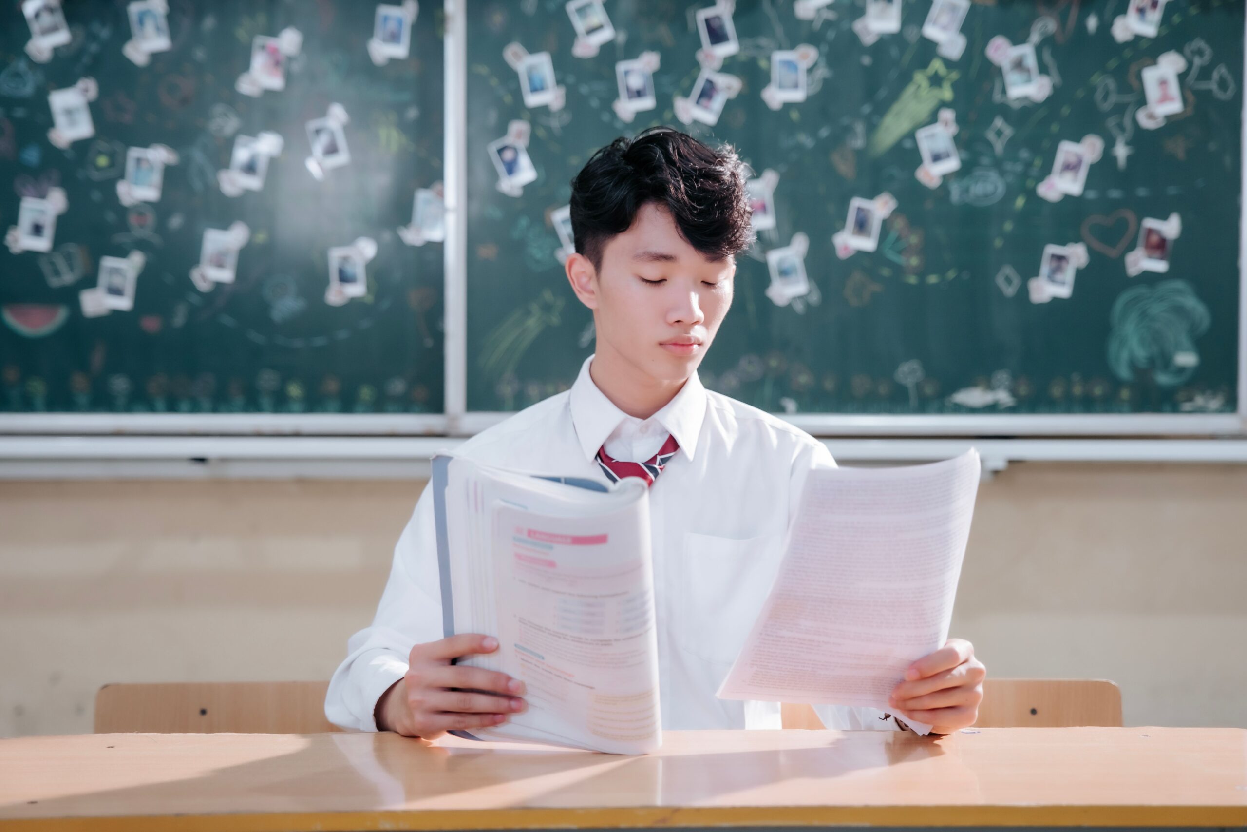 Teenage student reading papers at a classroom desk