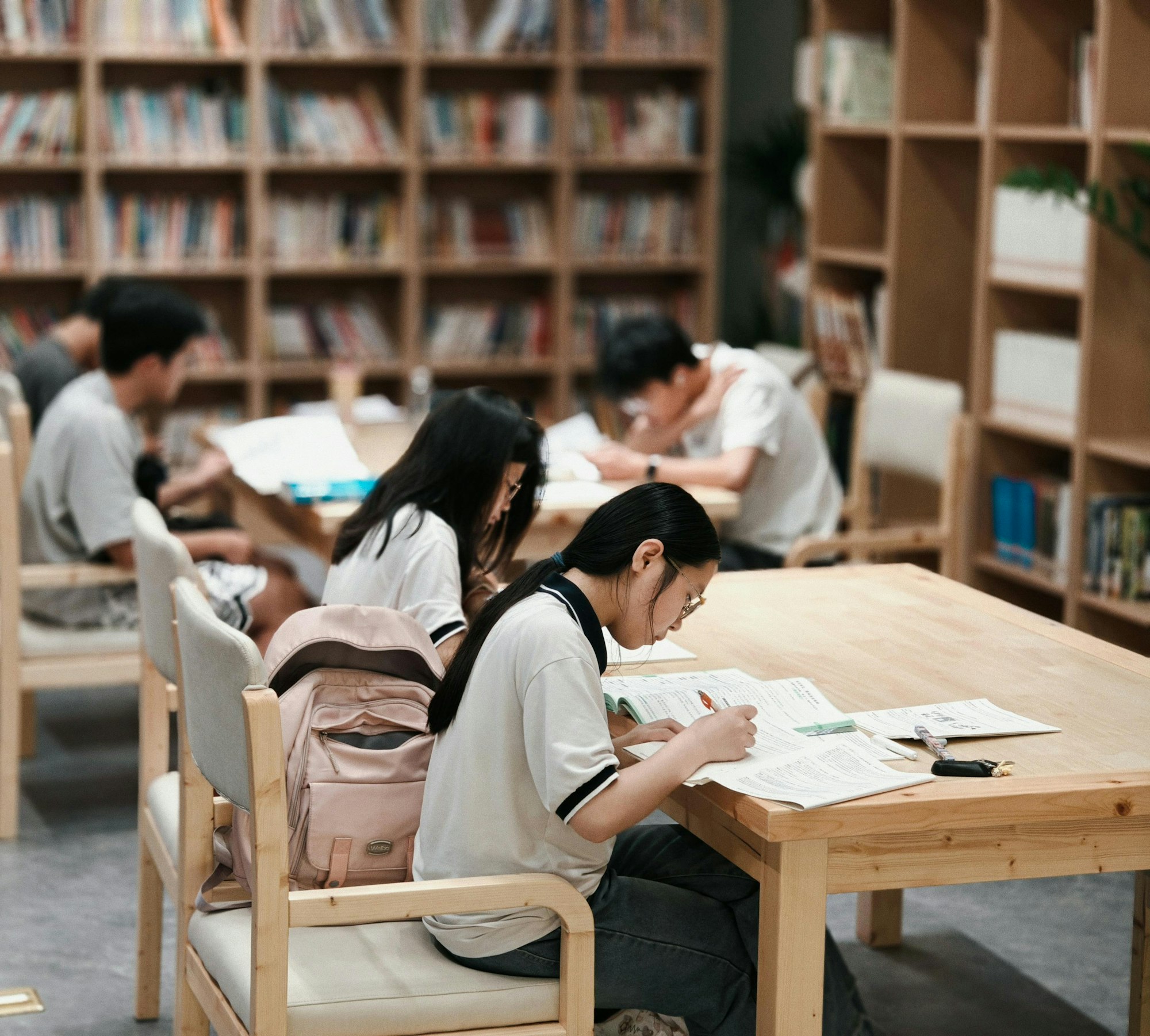 Students reading and writing at tables in a library