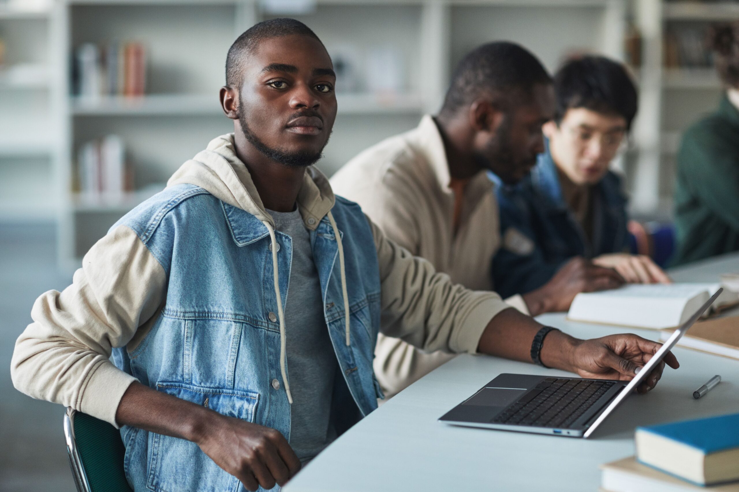 A group of college students using a laptop together in a university library