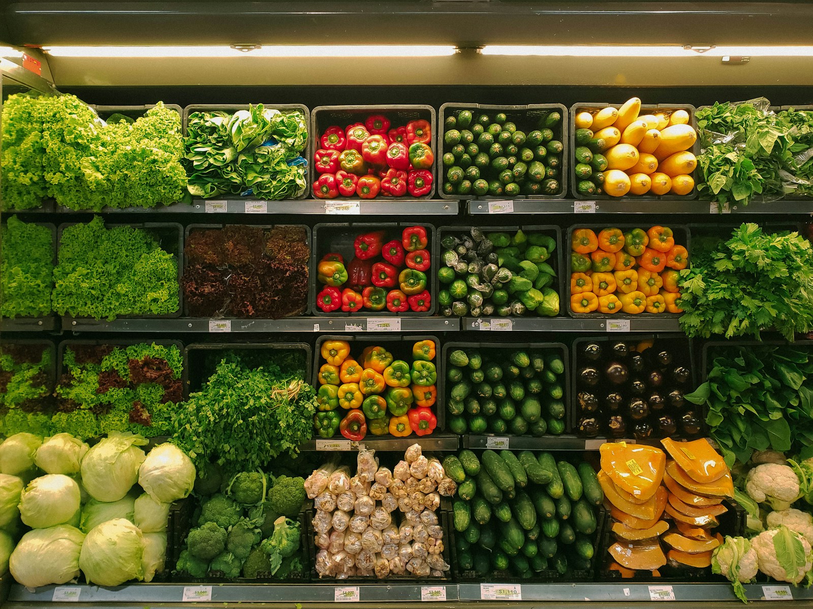 Shoppers choosing goods in a brightly lit supermarket produce section