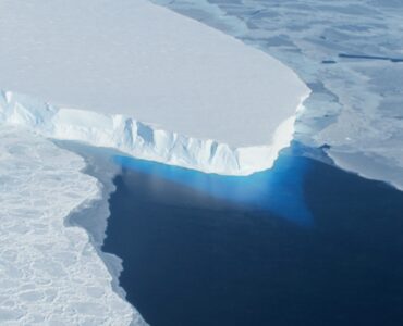 Aerial view of the blue-white calving front of Thwaites Glacier meeting the Antarctic Ocean
