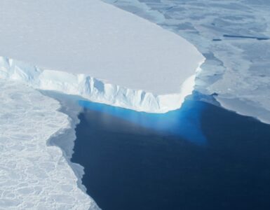 Aerial view of the blue-white calving front of Thwaites Glacier meeting the Antarctic Ocean