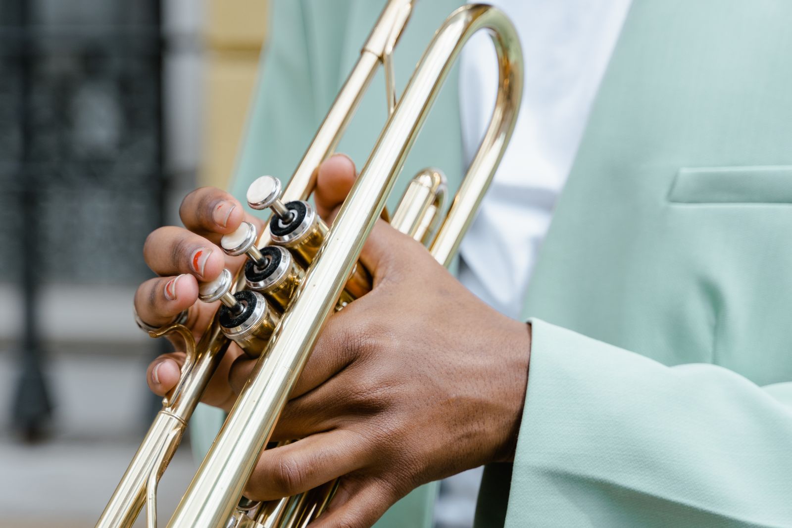 Musician's fingers pressing the three piston valves of a brass trumpet