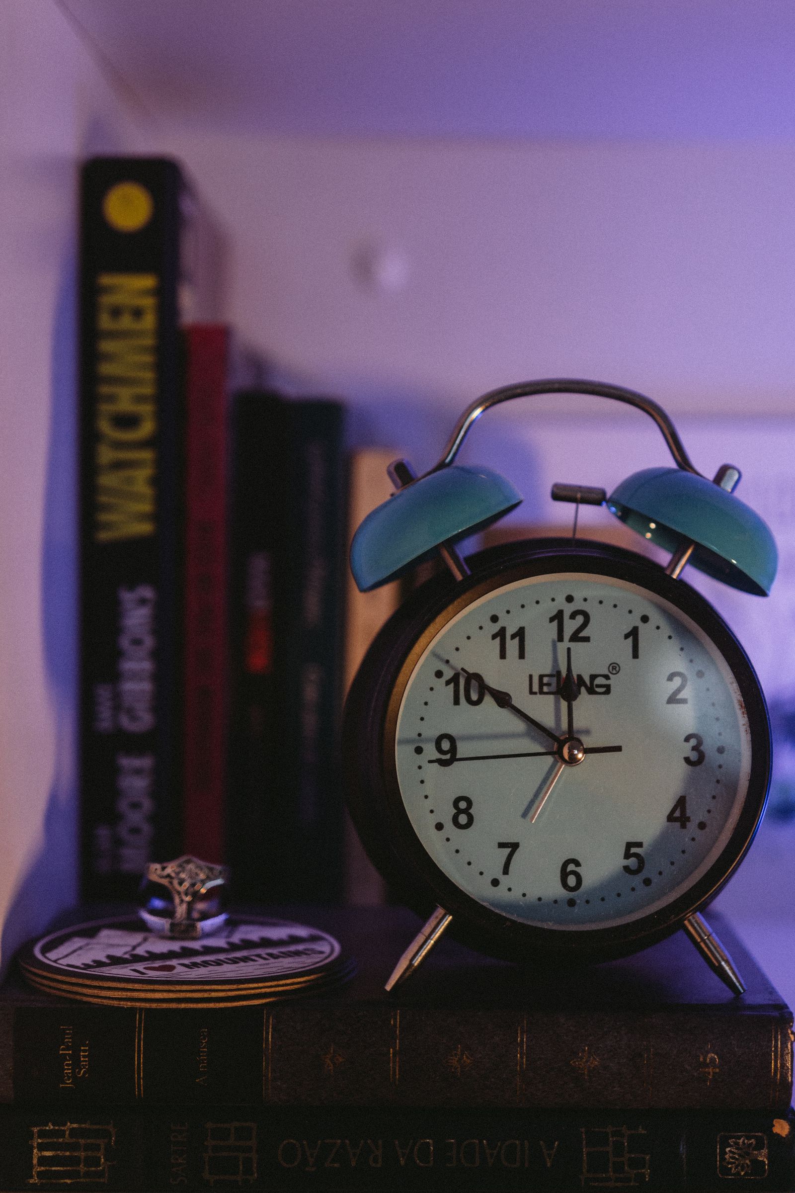 A vintage alarm clock resting on a stack of books