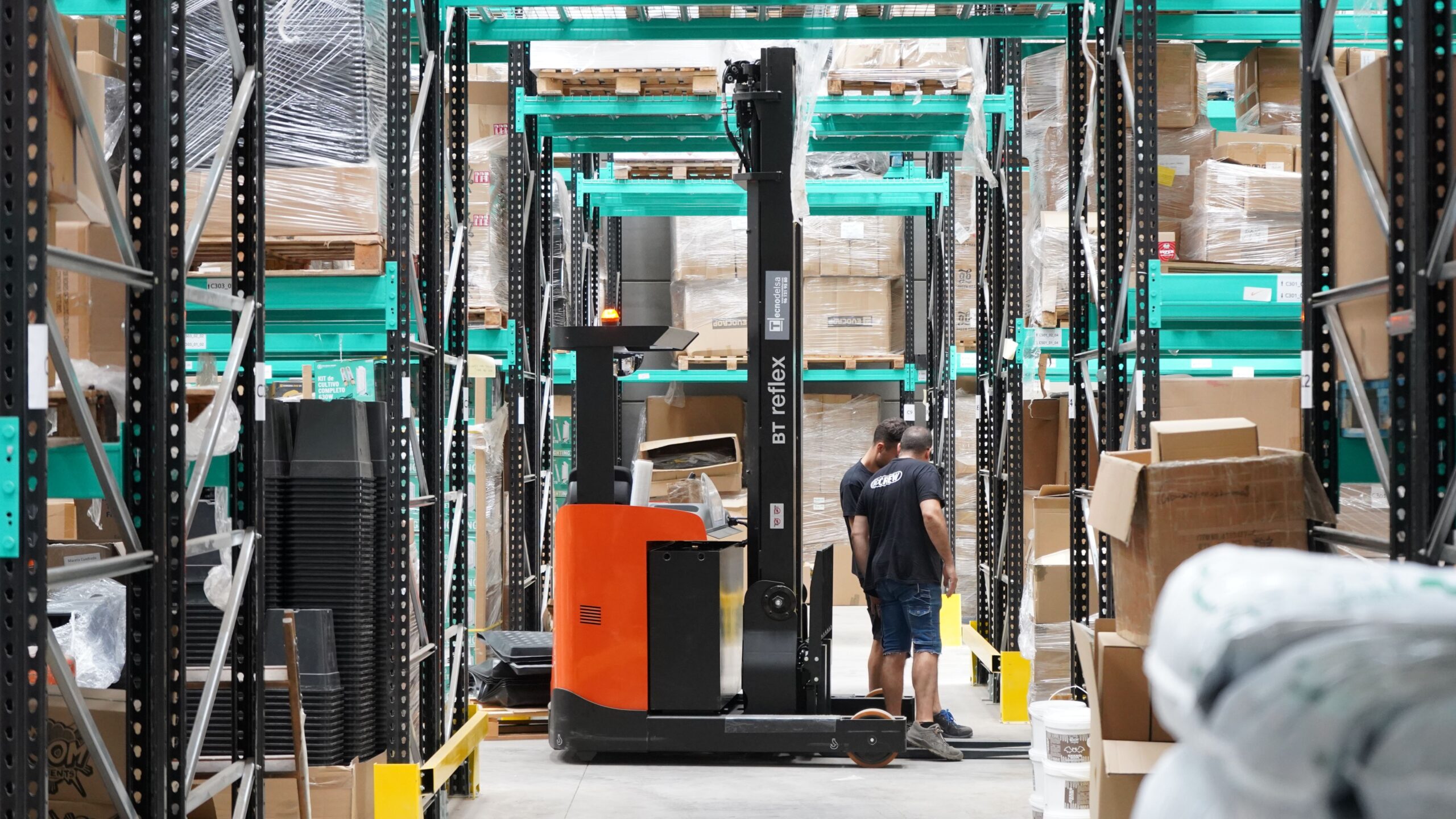 Workers and a forklift moving goods through a warehouse