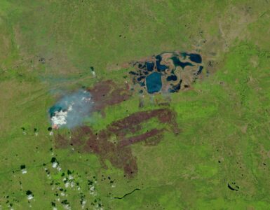 Satellite view of wildfire smoke spreading over a green landscape in western Canada