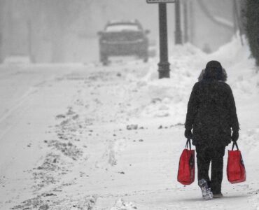 Bundled pedestrian walking through wind-driven snow in winter