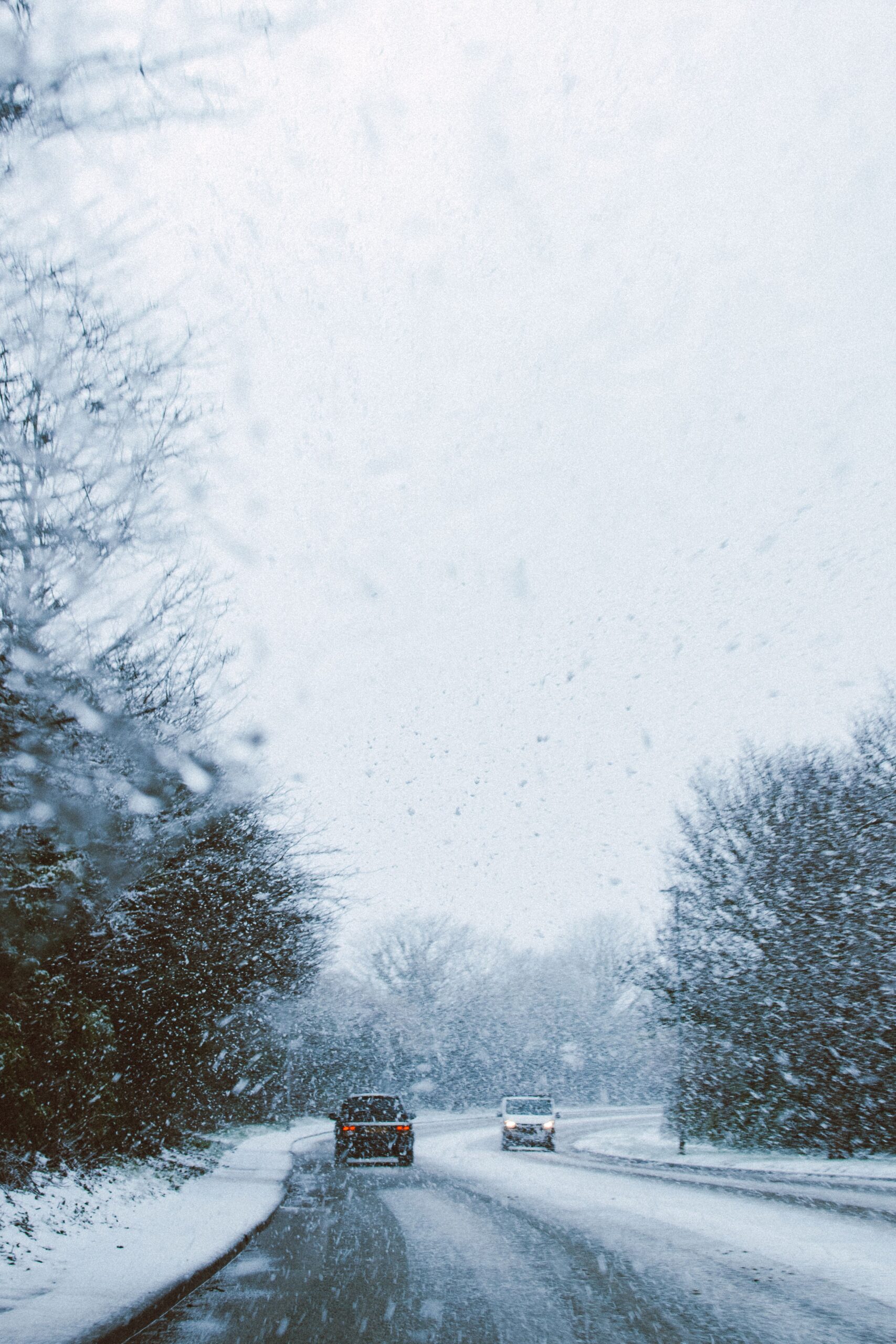 Cars traveling on a snowy road with limited visibility