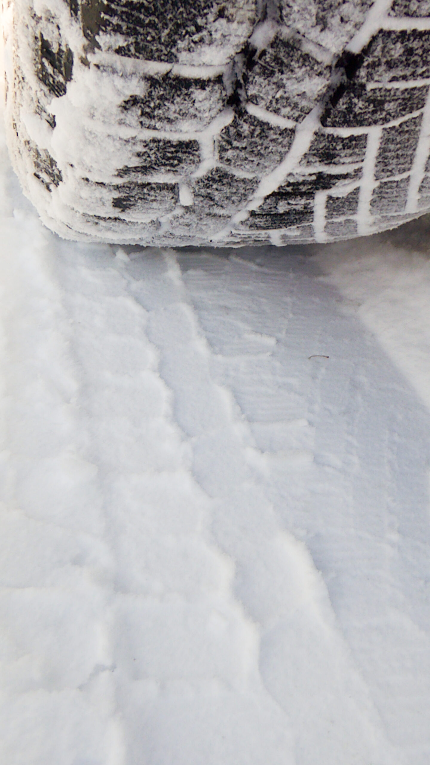 Winter tire beside the detailed tread imprint it left in compacted snow