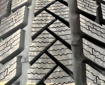 Close view of a winter tire's deep tread blocks and narrow sipes
