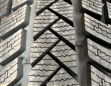 Close view of a winter tire's deep tread blocks and narrow sipes